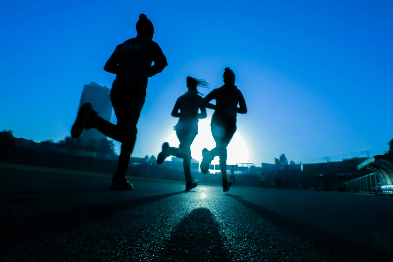 Runners in silhouette warming up at sunset